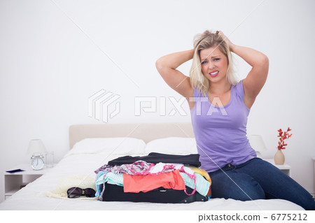 Young woman tearing her hair next to her full suitcase Young woman tearing her hair next to her full suitcase 6775212