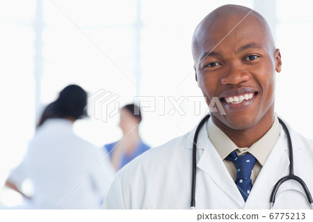 Smiling doctor standing with his stethoscope around his neck Smiling doctor standing with his stethoscope around his neck 6775213