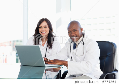 Two nurses working seriously while sitting at the desk in a well Two nurses working seriously while sitting at the desk in a well 6775264