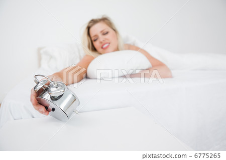 Woman looking at her alarm clock Woman looking at her alarm clock 6775265