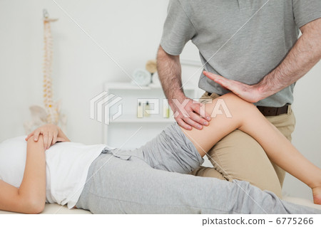 Serious osteopath massaging the knee of a patient Serious osteopath massaging the knee of a patient 6775266