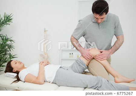 Black-haired osteopath touching the knee of a patient Black-haired osteopath touching the knee of a patient 6775267