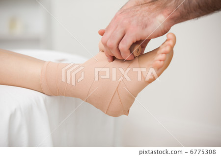Practitioner bandaging an ankle Practitioner bandaging an ankle 6775308