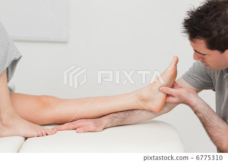 Physiotherapist looking at the foot of a patient Physiotherapist looking at the foot of a patient 6775310