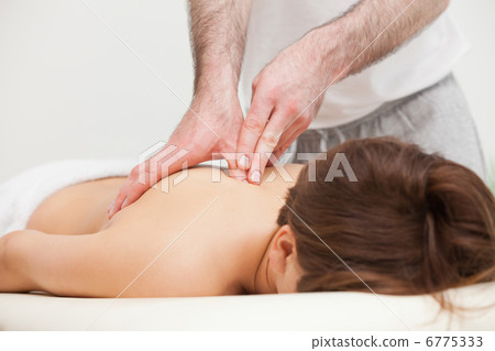 Therapist massaging the top of back of woman while standing Therapist massaging the top of back of woman while standing 6775333