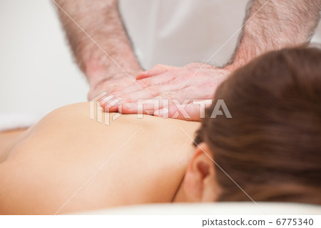 Close-up of a doctor massaging the back of a woman Close-up of a doctor massaging the back of a woman 6775340