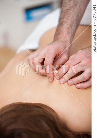 Back of a woman being massaging while fingertips of doctor 6775341