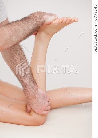 Podiatrist manipulating the leg of his patient while holding his Podiatrist manipulating the leg of his patient while holding his 6775346