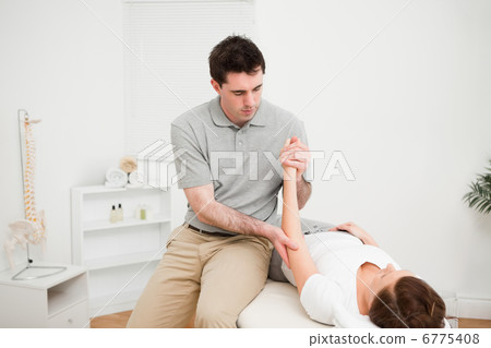 Doctor examining the arm of his patient while touching his elbow Doctor examining the arm of his patient while touching his elbow 6775408