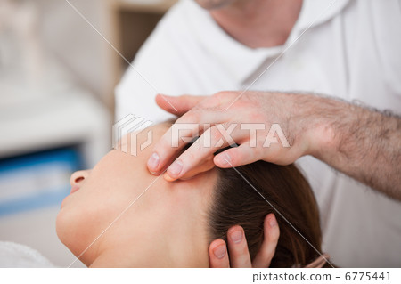 Doctor manipulating the side of the head of his patient 6775441