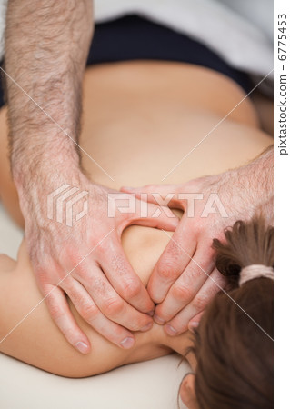 Osteopath pressing the shoulders of his patient while using his Osteopath pressing the shoulders of his patient while using his 6775453