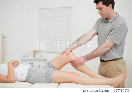 Physiotherapist examining the knee of his patient while touching Physiotherapist examining the knee of his patient while touching 6775473