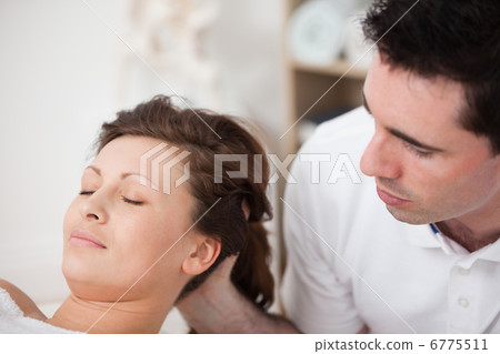 A doctor massaging the head of his patient while holding it 6775511