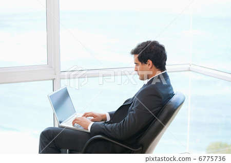 Man sitting on a chair while typing on a computer 6775736