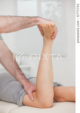 Physiotherapist bending the led of a woman Physiotherapist bending the led of a woman 6775742