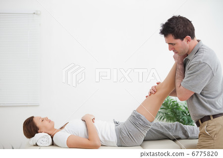 Chiropractor massaging a leg while placing it on his shoulder Chiropractor massaging a leg while placing it on his shoulder 6775820