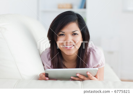Woman smiling while resting on a couch and playing with a tablet Woman smiling while resting on a couch and playing with a tablet 6775821