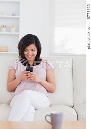 Woman sitting on a couch and holding a phone Woman sitting on a couch and holding a phone 6775823