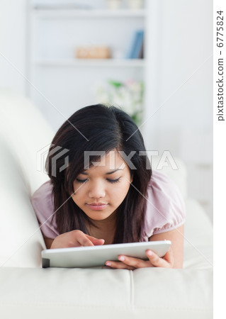Woman touching a tablet while resting on a sofa Woman touching a tablet while resting on a sofa 6775824