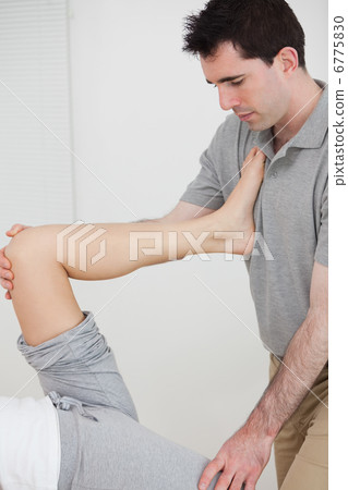 Physiotherapist stretching a leg while placed it on his chest Physiotherapist stretching a leg while placed it on his chest 6775830