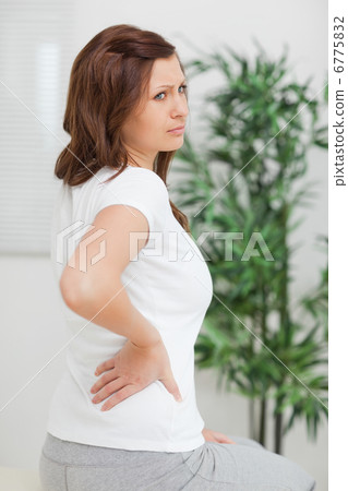 Woman touching her back while looking away Woman touching her back while looking away 6775832