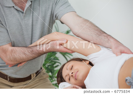 Woman being stretched while lying on a table Woman being stretched while lying on a table 6775834