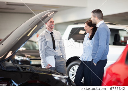 Salesman smiling as he talks to a couple Salesman smiling as he talks to a couple 6775842