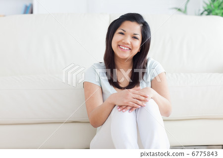 Woman smiles as she sits on the floor in a living room Woman smiles as she sits on the floor in a living room 6775843