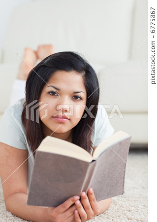 Woman holding a book while lying on the floor Woman holding a book while lying on the floor 6775867