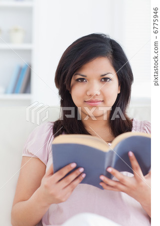 Woman reading a book while she sits on a couch 6775946