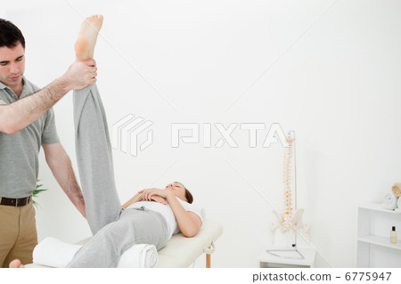 Physiotherapist raising the leg of a woman Physiotherapist raising the leg of a woman 6775947
