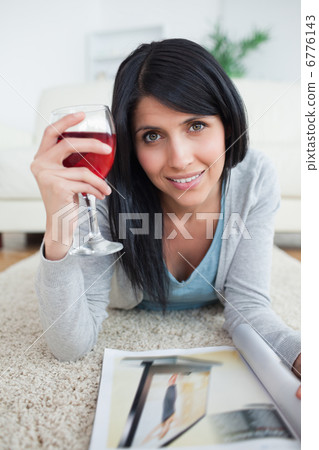 Woman smiling while holding a magazine and a glass of red wine Woman smiling while holding a magazine and a glass of red wine 6776143