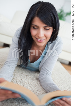 Smiling woman reading a book while lying on the floor Smiling woman reading a book while lying on the floor 6776151