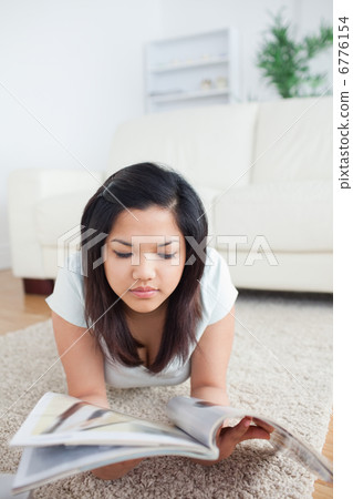 Woman reading a magazine on the floor Woman reading a magazine on the floor 6776154