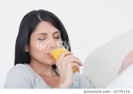 Woman closing her eyes while drinking a glass of orange juice 6776158