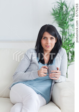 Woman relaxing on a sofa while holding a grey mug 6776268