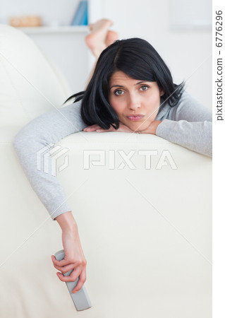 Sad woman on a sofa holding a television remote Sad woman on a sofa holding a television remote 6776296