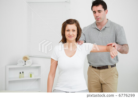 Doctor examining the shoulder of his patient while holding his a Doctor examining the shoulder of his patient while holding his a 6776299