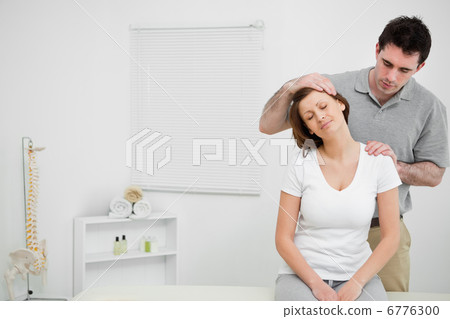 Doctor examining the neck of his patient while stretching it Doctor examining the neck of his patient while stretching it 6776300
