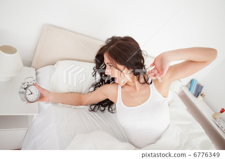 Tired woman holding her alarm clock Tired woman holding her alarm clock 6776349
