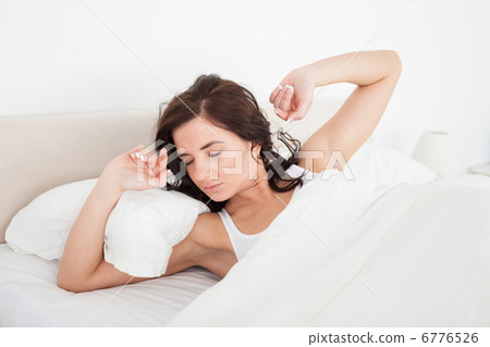 Brunette woman stretching her arms while lying 6776526