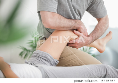 Man manipulating the leg of a woman while she is lying Man manipulating the leg of a woman while she is lying 6776767