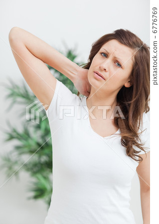 brunette standing while placing her hand on her neck brunette standing while placing her hand on her neck 6776769