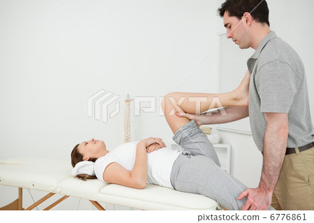 Osteopath stretching the leg of his patient Osteopath stretching the leg of his patient 6776861
