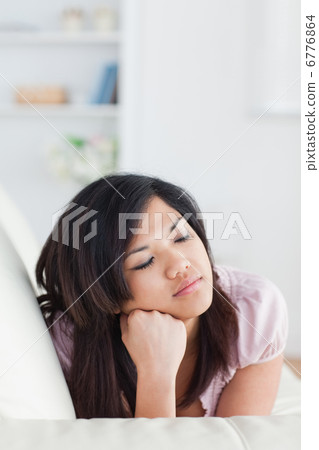Woman lying on a sofa while holding her head Woman lying on a sofa while holding her head 6776864
