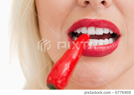 Blonde woman biting a red chili pepper 6776908