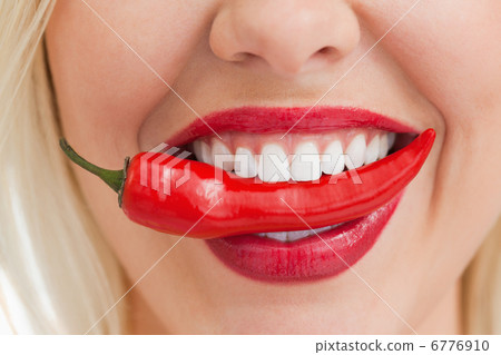 Happy blonde woman holding a chili with her mouth Happy blonde woman holding a chili with her mouth 6776910