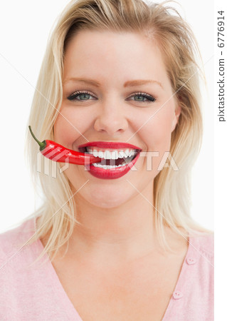 Happy blonde woman biting a chili Happy blonde woman biting a chili 6776914