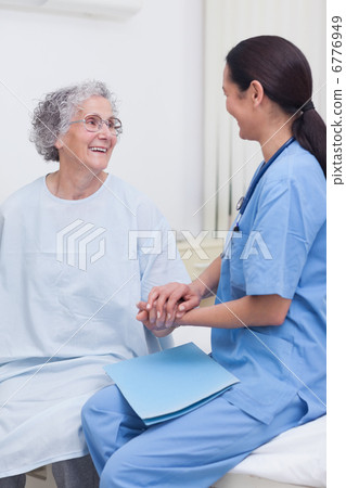 Nurse sitting on bed with a patient 6776949