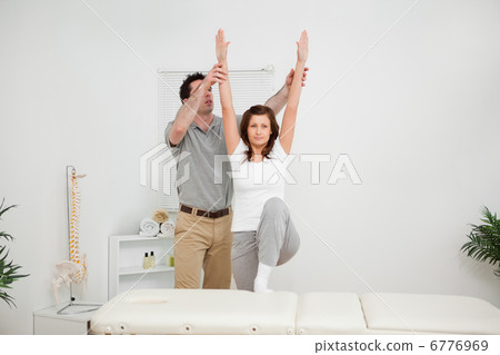Brunette doing stretching exercises with a physiotherapist Brunette doing stretching exercises with a physiotherapist 6776969